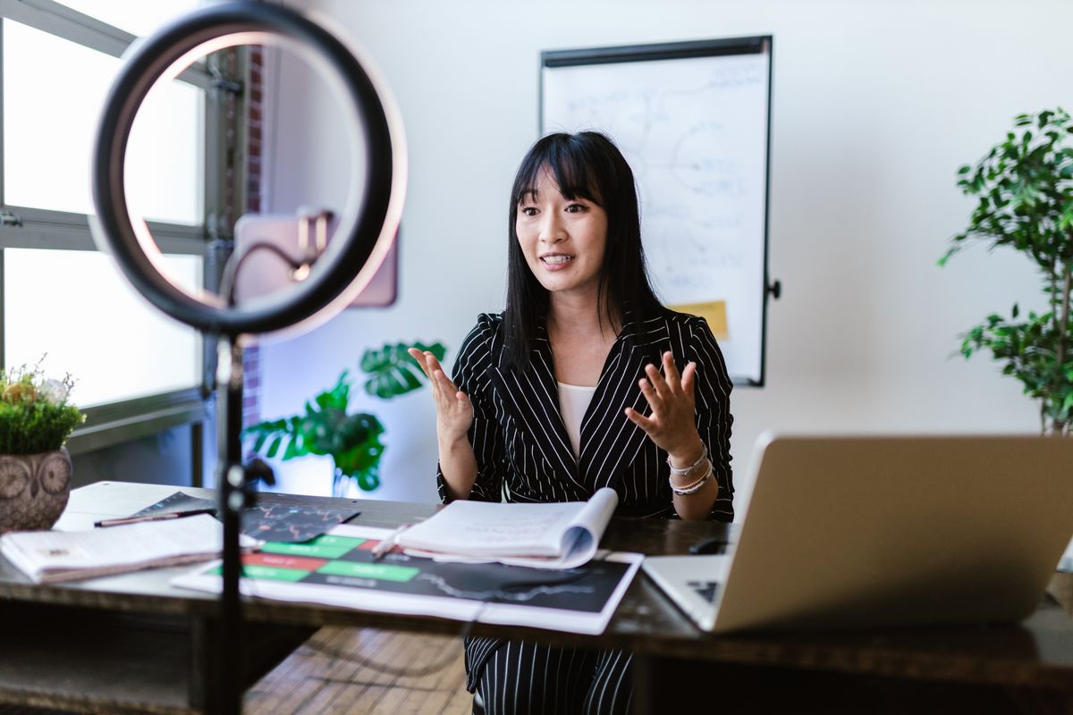 Creator speaking toward a phone camera with a ring light and laptop